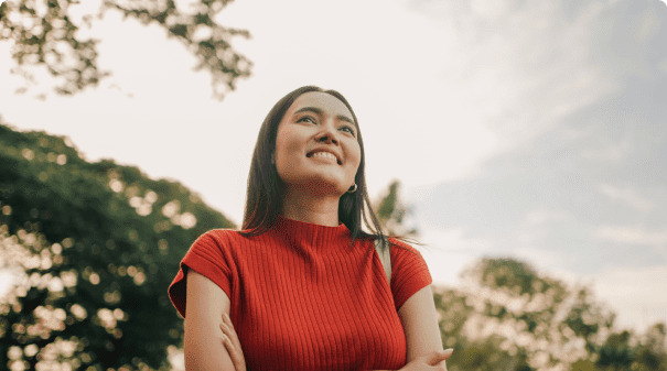 Smiling woman in red shirt outdoors.