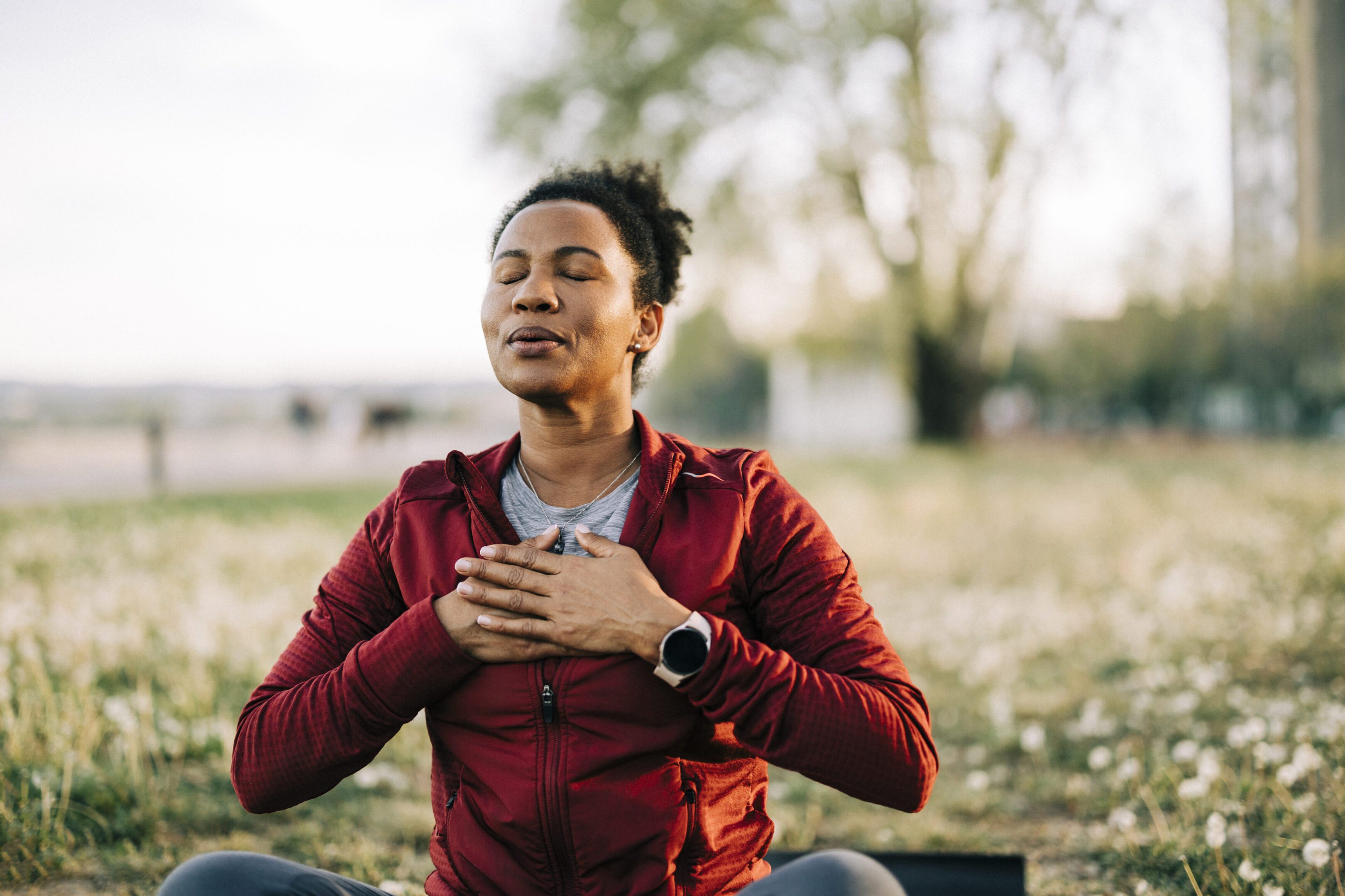 Person meditating outdoors, eyes closed, peaceful expression.