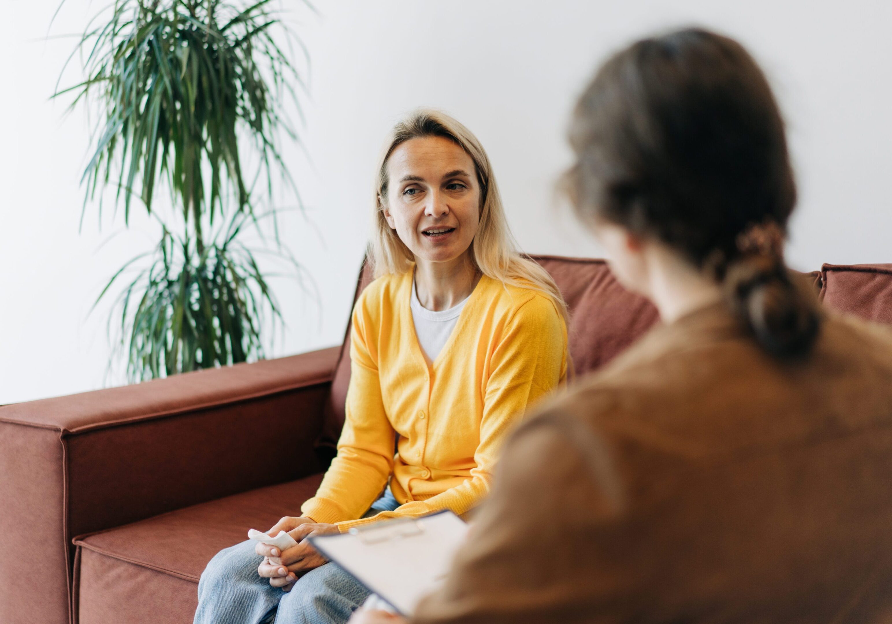 Two people talking on a couch indoors.